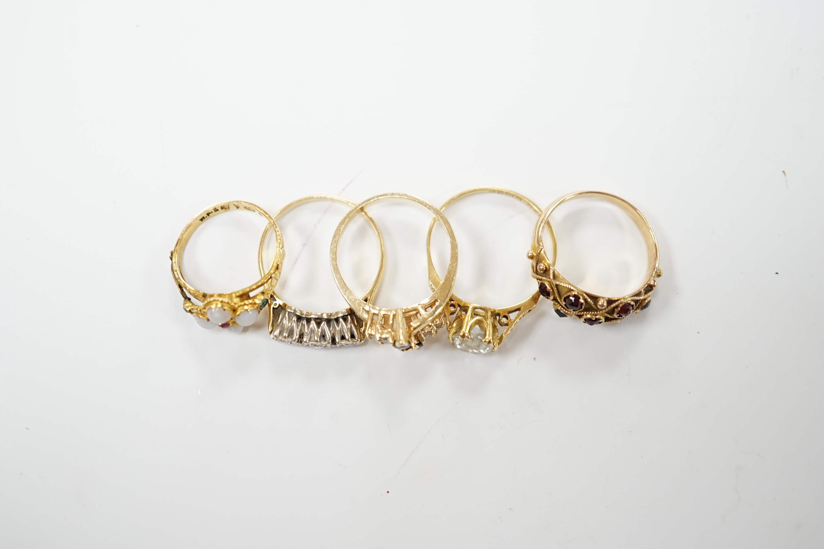 An Edwardian 15ct?, white opal, emerald and amethyst cluster set ring, in the Suffragette colours, size F, together with four other yellow metal and gem set rings including three stone illusion set diamond and a 14k sapp